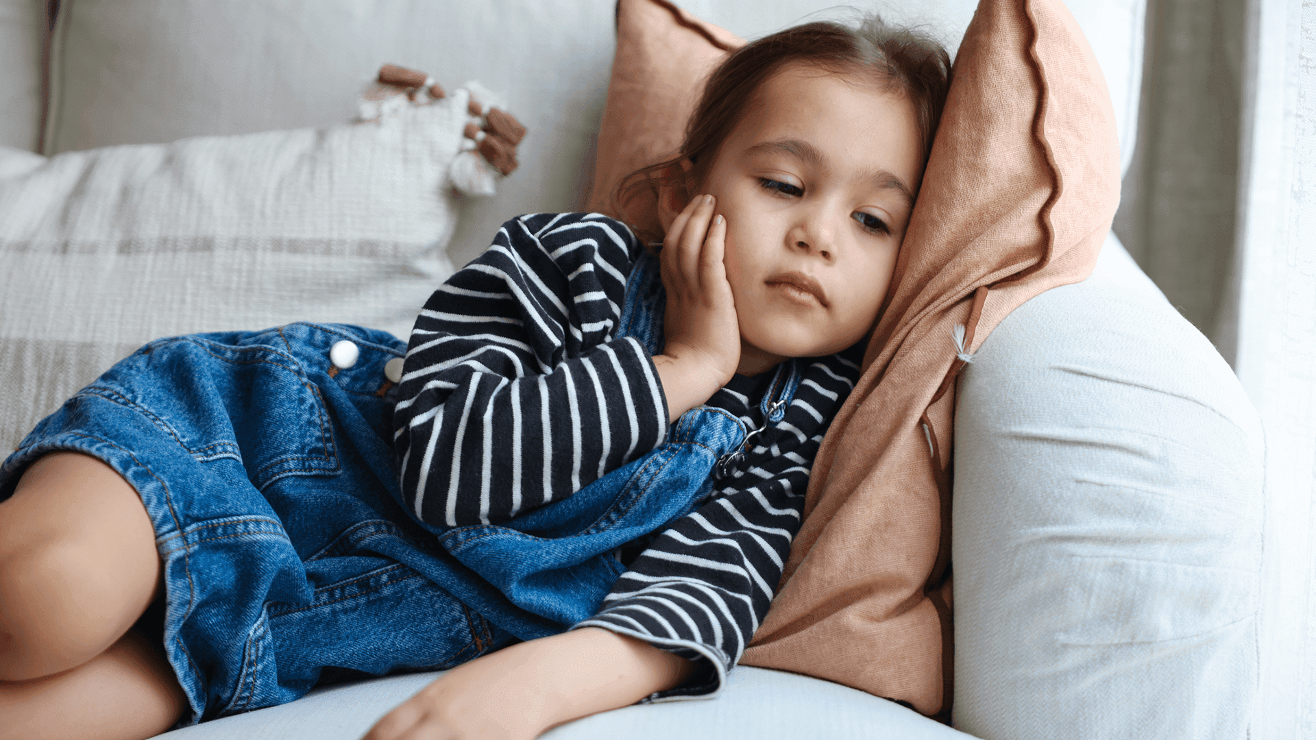 Young sick child laying on couch in pain