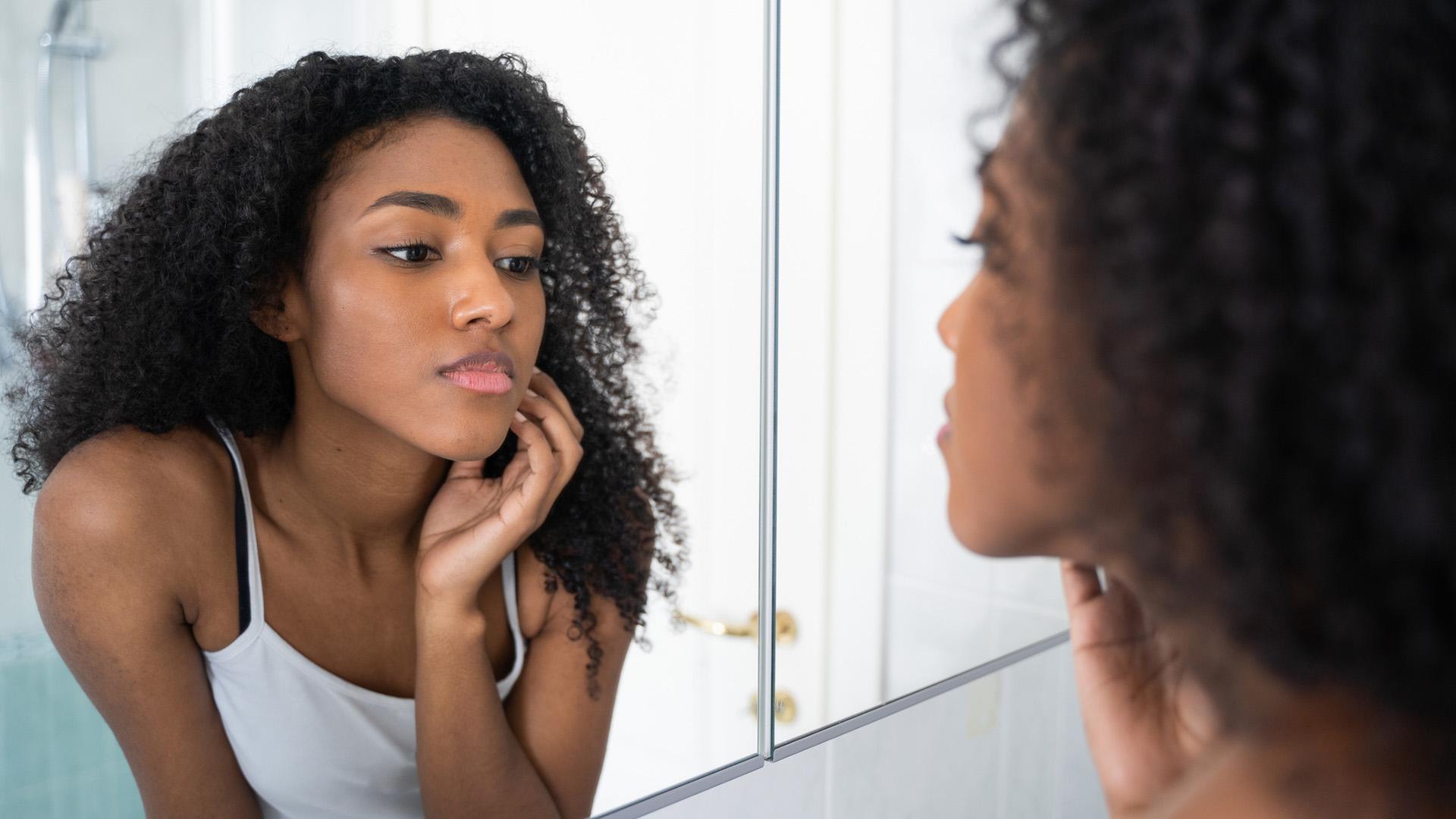 One black woman looking skincare mirror